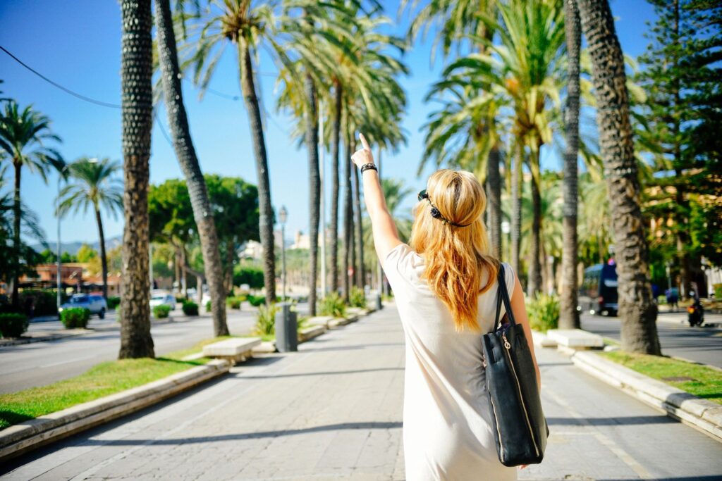 Blonde walking away from camera with arm raised in a sunny, warm setting for affirmations article.