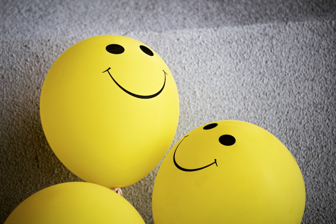 Yellow smiley balloons on gray textile for definition of positivity 