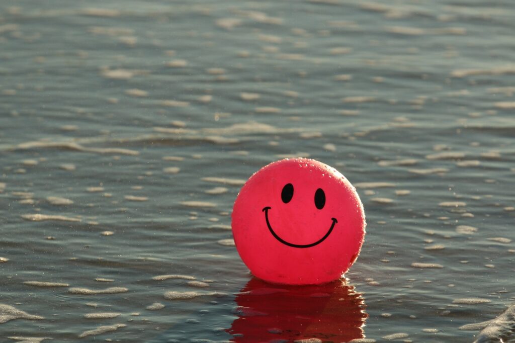 Smiling ballon floating in water representing a fake smile 